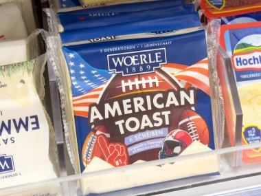 Süpermarket vitrininde Amerikan tost peyniri paketleri ve futbol temalı ambalajlar.