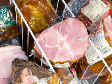 Market vitrininde çeşitli paketlenmiş jambon ve et parçaları.
