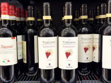 Sergilenen rafta İtalyan kırmızı şarap şişeleri var..