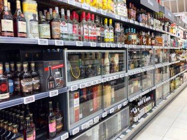 Süpermarket koridorundaki raflarda çeşitli alkollü içecekler var..