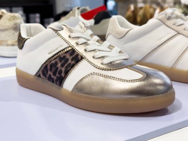 Leopar desenli beyaz ve altın renkli spor ayakkabılar..