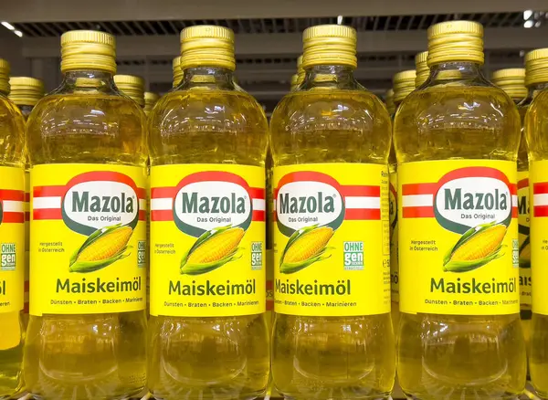 Mazola mısır yağı şişeleri sarı etiketli ve kırmızı çizgili raflarda..