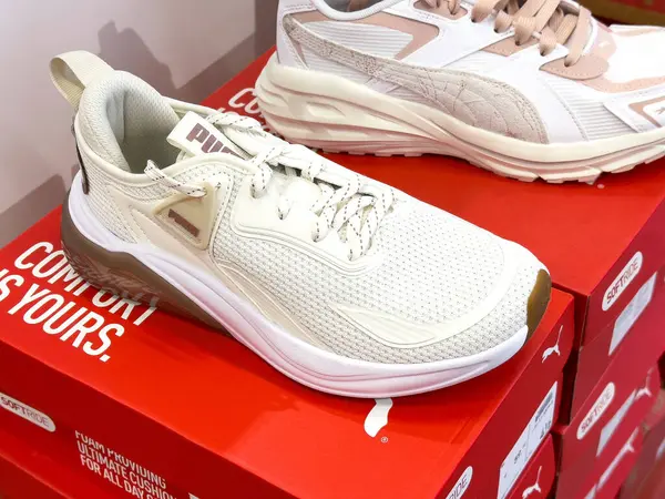 Mağazadaki kırmızı kutularda gösterilen beyaz puma spor ayakkabıları.