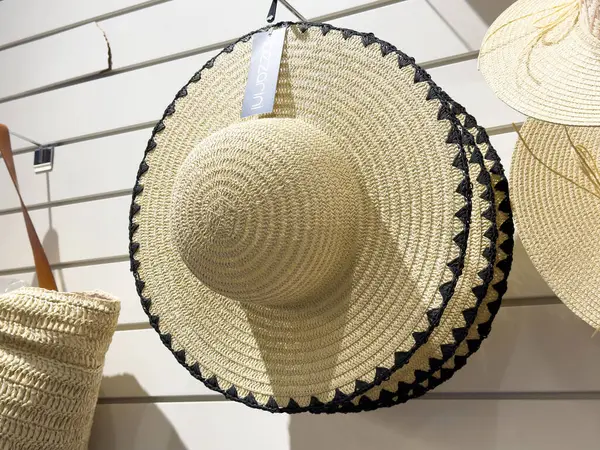 Mağazada asılı duran siyah süslemeli büyük hasır şapka.