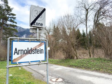Arnoldstein köyünün son işareti manzaralı dağ ve arka planda ağaçlar.