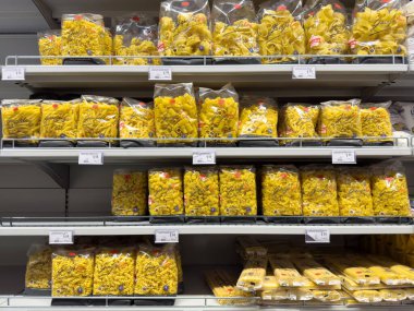 Süpermarket raflarında geniş çeşitte paketlenmiş makarna.