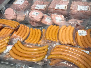 Dondurulmuş vitrindeki paketlenmiş sosisler ve salamlar çeşitliliği.