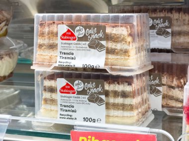 Süpermarketin soğutmalı vitrininde paketlenmiş tiramisu keki dilimleri.