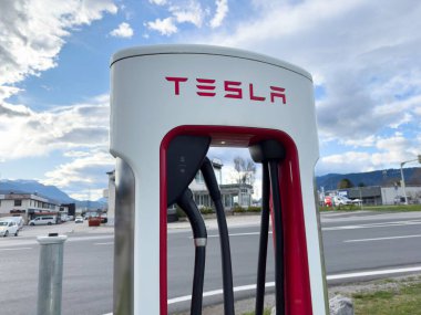 Tesla elektrikli otomobil şarj istasyonu. Şehirdeki dağların yakınında bulutlu bir günde..