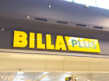 Modern alışveriş merkezinde parlak sarı billa artı işareti.