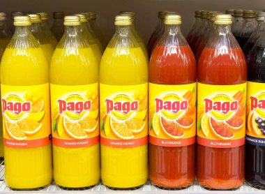 Bir mağazanın rafında çeşitli meyve aromalı renkli pago suyu şişeleri.