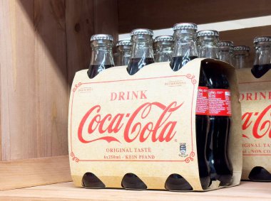 Coca-Cola cam şişeleri vitrindeki ahşap rafta duruyor..