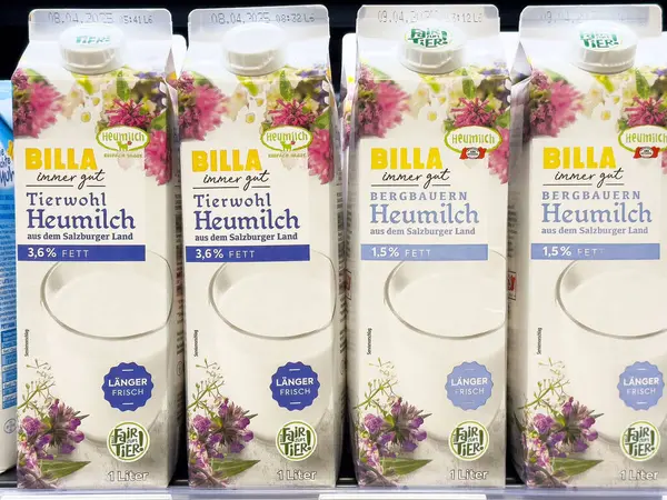 Çiçek tasarımı ve tazelik etiketli Billa süt kutuları sergileniyor.