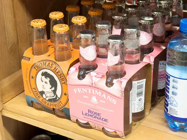 Bir şişe Thomas Henry, pembe greyfurt ve Fentiman çiçekleri ahşap rafta limonata..
