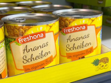 Meyve suyunda konserve ananas dilimleri ve rafta parlak ambalajlar..