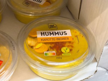 Plastik kabın içinde havuç ve zencefilli humus. Üzerinde beslenme etiketi var..