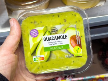 Plastik kabın içinde avokado ve domates betimlemesiyle hafif vejetaryen guacamole..