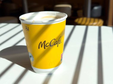 Mccafe kahve fincanı güneşli masada, sanatsal gölgelerle..