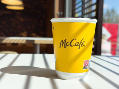 Kafe ortamında güneş ışığı masasında Mccafe sarı kahve fincanı.