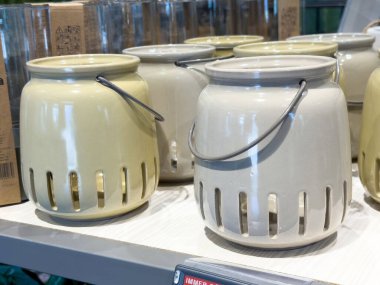 Rafta tutacakları olan bej ve sarı seramik fenerler..