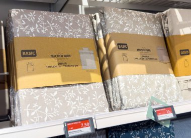 Fiyat etiketli mikrofiber yatak örtüsü setleri mağaza rafında görüntülenir.