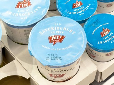 Süpermarkette mavi kapaklı organik Avusturyalı yoğurt konteynırları.