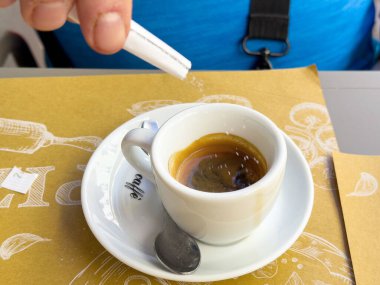 Beyaz bardakta espresso 'ya şeker ve kaşık ekliyorum..