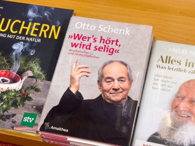 Olgun beyaz bir erkek, elinde Otto Schenk 'in portresiyle mutluluk ve doğa üzerine kitap tutuyor..