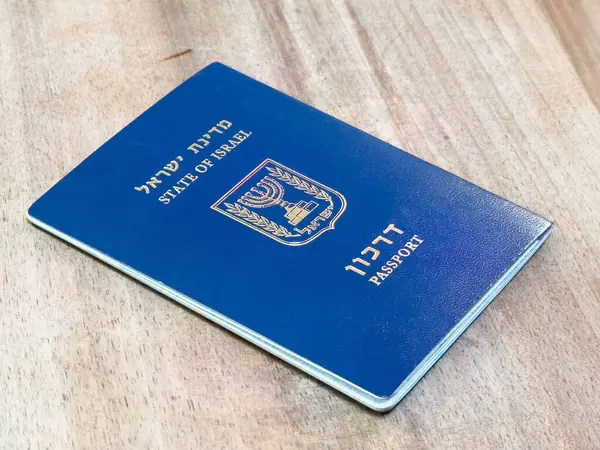 Ahşap yüzeyde İsrail pasaportu ve mavi kapaklı devlet amblemi..
