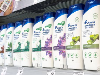 Kafada ve omuzlarda çeşitli koku ve formüllerle sergilenen şampuan şişeleri.