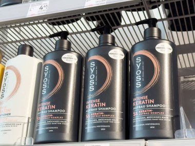 Fiyat etiketli ambar rafında yoğun keratin şampuan şişeleri.