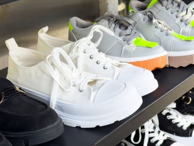 Şık ayakkabı koleksiyonu arasında sergilenen beyaz tuval spor ayakkabıları.