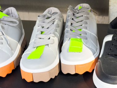 Neon yeşil aksanlı ve turuncu tabanlı modaya uygun gri ayakkabılar..