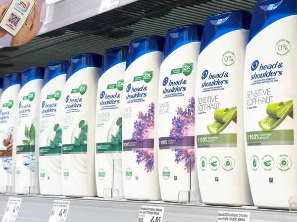 Kafada ve omuzlarda çeşitli koku ve formüllerle sergilenen şampuan şişeleri.
