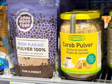 Market rafında organik çiğ kakao ve keçiboynuz tozu paketleri.