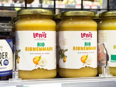 Rafta sarı etiketli organik armut püre kavanozları sergileniyor.