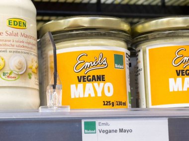 Vejetaryen mayonez kavanozları sarı etiketli raflarda duruyor..