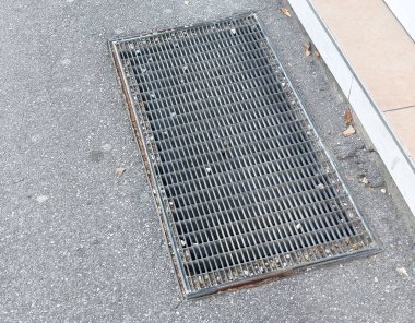 Kaldırım yüzeyindeki metal ızgara yapraklar ve enkazlarla bitişik kaldırım..