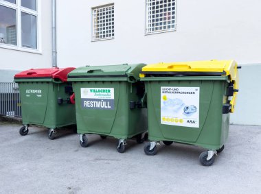 Kırmızı, yeşil ve sarı kapaklı üç yeşil geri dönüşüm kutusu..