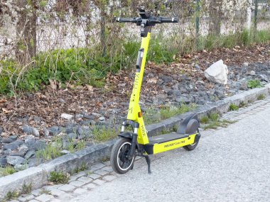 Yol kenarına park edilmiş sarı elektrikli scooter..