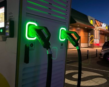 Geceleri parlayan yeşil konnektörleri olan elektrikli araç şarj istasyonu.