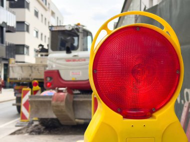Şehir caddesinde kırmızı ışık ve makineli kentsel inşaat sahnesi.