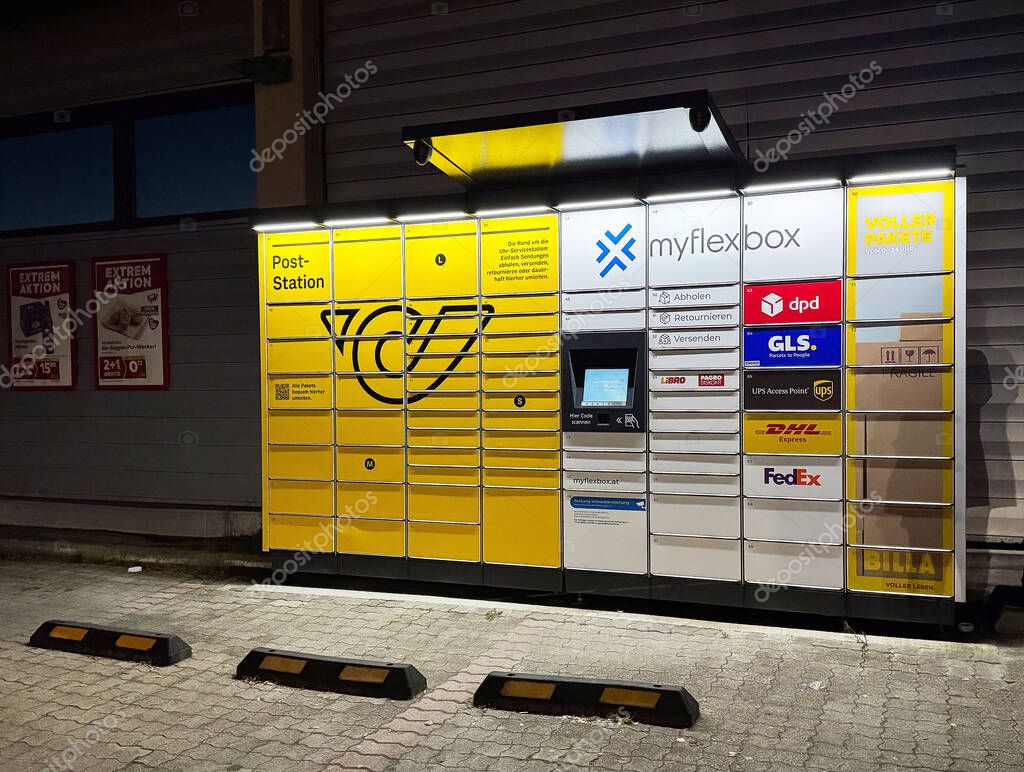 Yellow parcel locker at night with various courier logos.