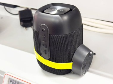 Kontrol düğmeleri ve sarı şeritli küçük siyah bluetooth hoparlör.