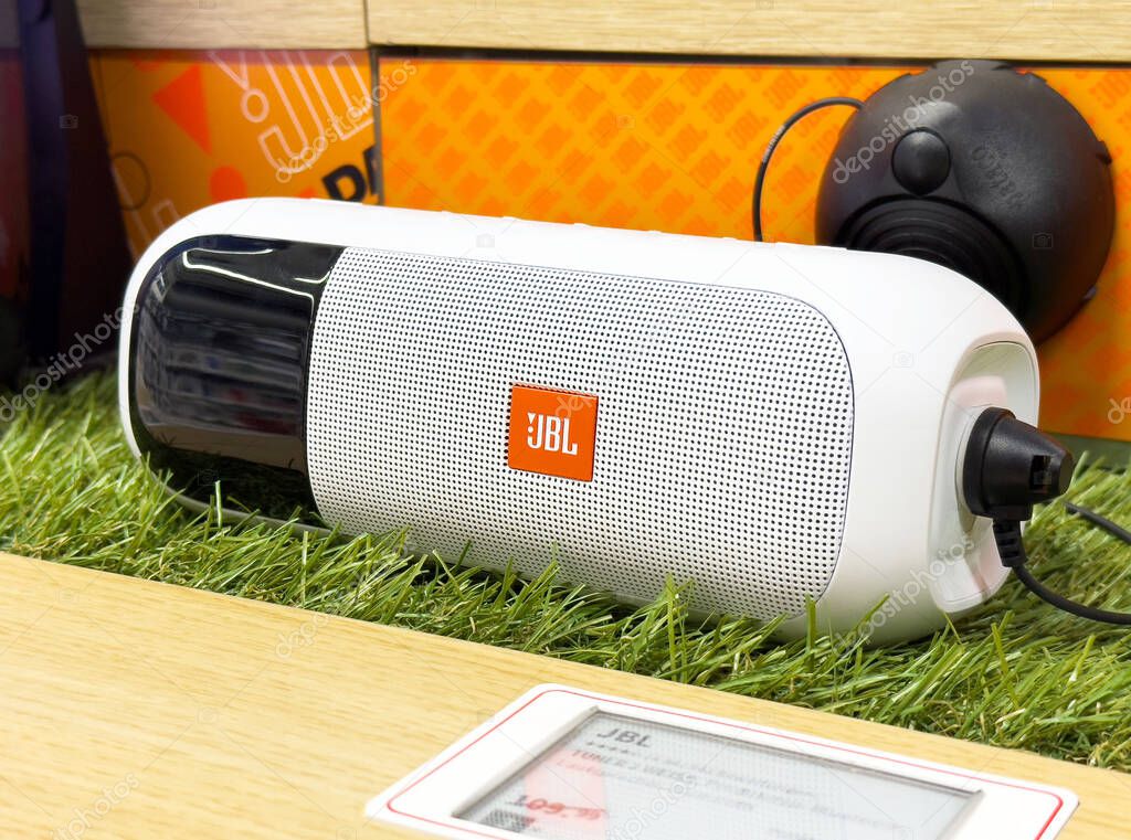 Portable jbl bluetooth speaker on display shelf with charging cable.