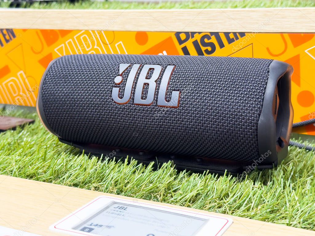 Jbl bluetooth speaker on green grass with orange branding background.