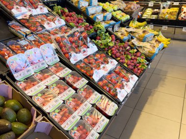 Süpermarket koridorunda kiraz domatesleri, erikler ve muzlarla taze ürünler sergileniyor..