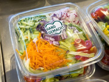 Açık plastik kabın içinde el yapımı etiketli renkli taze karışık salata..