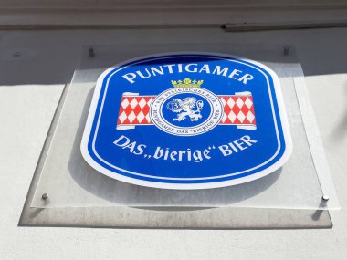 Duvarda mavi ve kırmızı logolu Puntigamer bira tabelası.