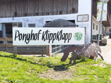 Kırsal ahır ve dekoratif at heykeli olan Ponyhof klippklapp giriş tabelası.